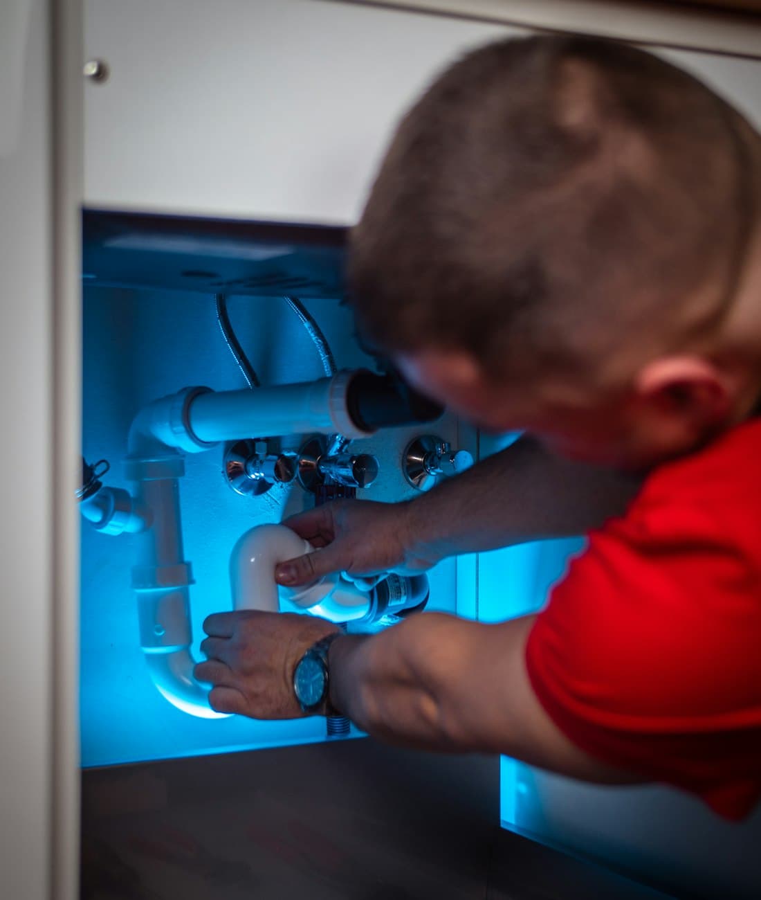 Installateur sanitaire d'Eau-Solutions Sàrl travaillant sur une installation de tuyauterie
